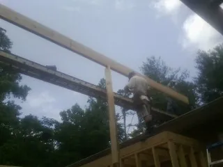 Carpenter setting a ridge beam over a new addition frame — Ice Dam Removal by Roofing Brothers in Wylie