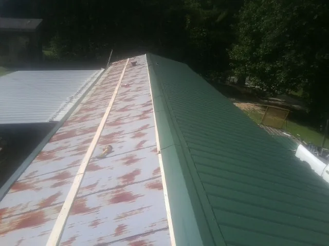 Old rusted panels beside newly installed green metal roofing — Wind Damage Roof Repair by Roofing Brothers in Wylie