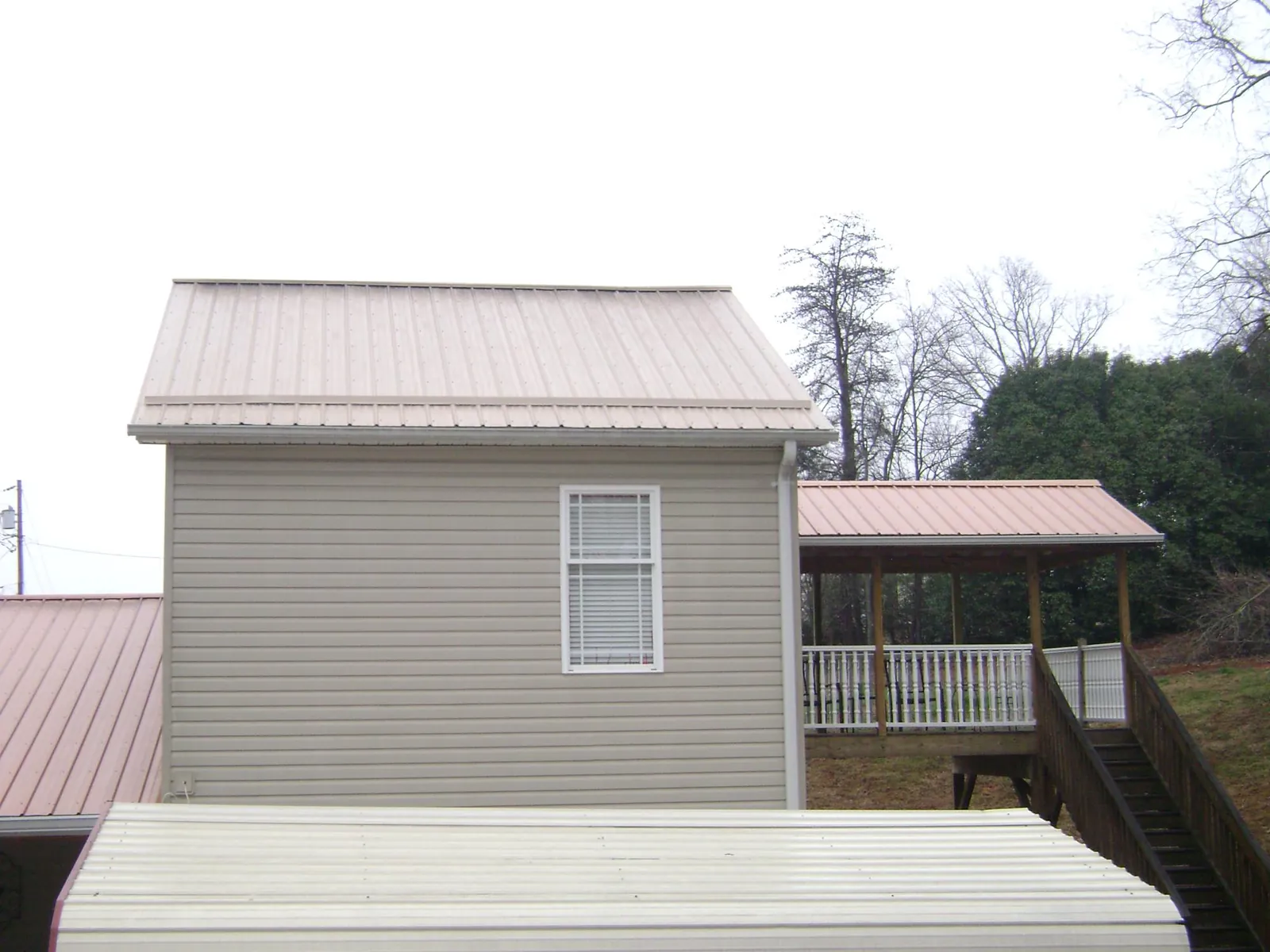 Tan metal roofs on a two story addition and attached porch, from a Roof Replacement job in Wylie