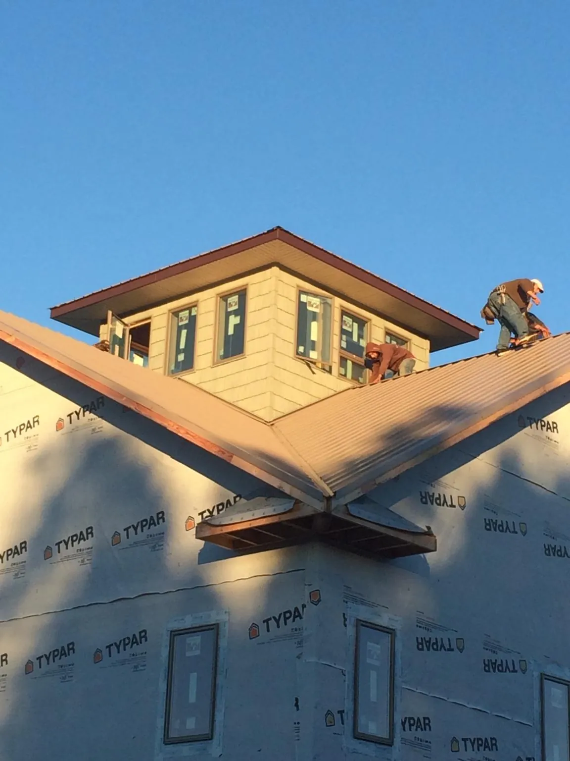 Roofers working around a rooftop cupola on a new metal roof at sunset — Roof Waterproofing in Wylie by Roofing Brothers